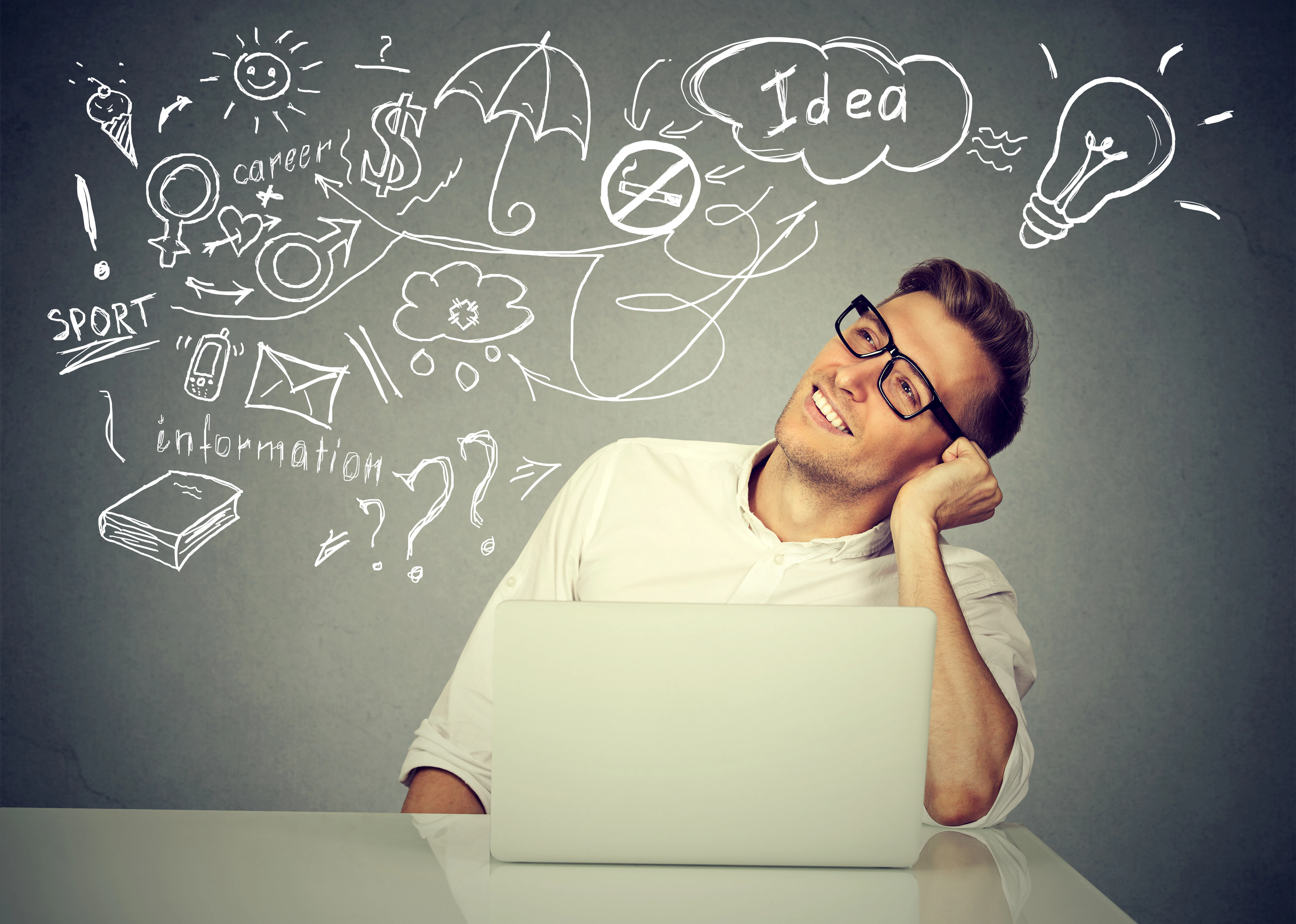 Closeup portrait happy young man working on computer thinking dreaming has many ideas isolated on gray background. Positive human face expression emotion. Decision making concept