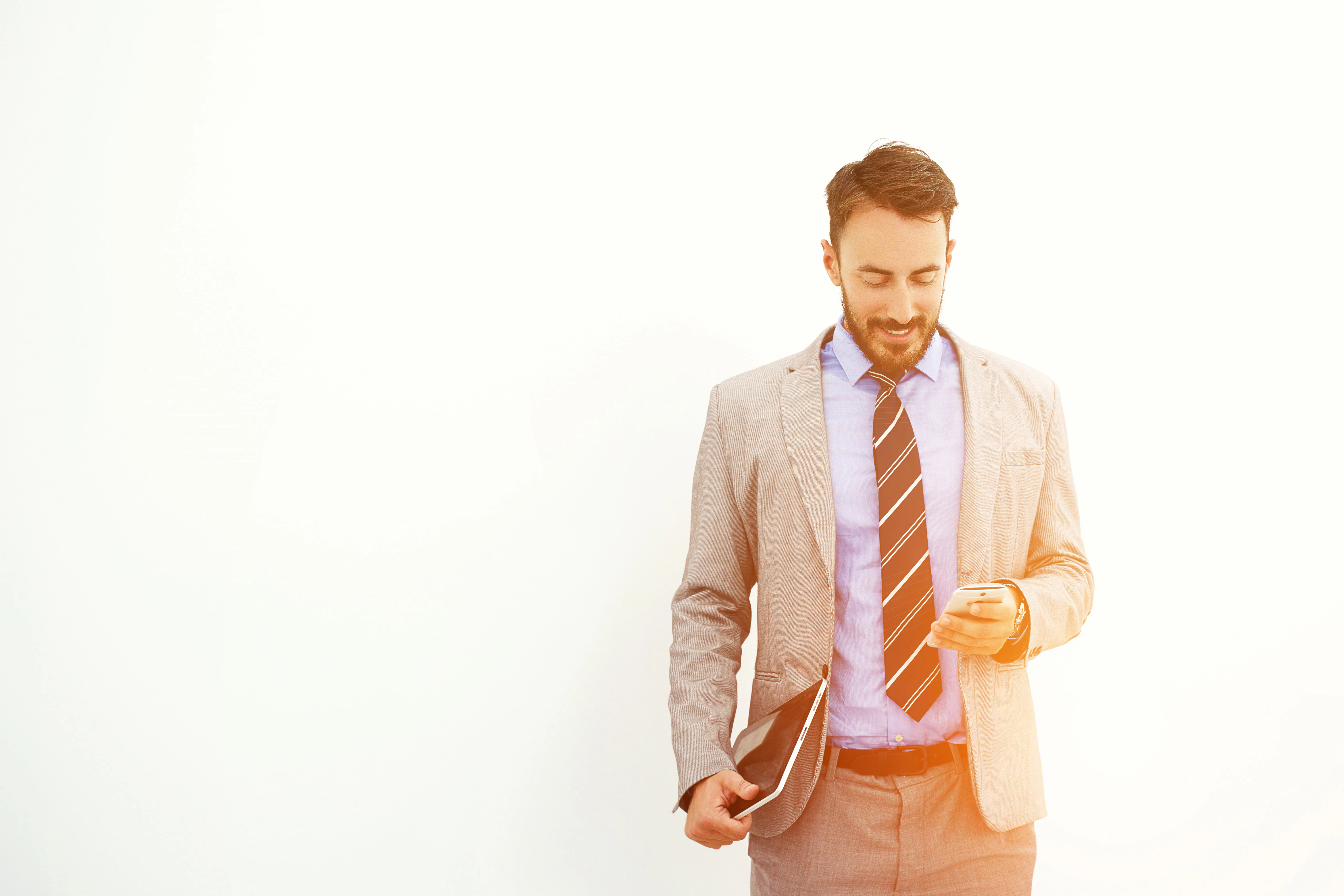 Man professional trader with digital tablet in hand is reading good news on mobile phone from his client about purchase of securities, while is standing near copy space for your advertising text